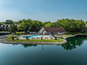 a backyard with a pool and a house next to a lake at Bavarian Village Apartments, Indianapolis, Indiana
